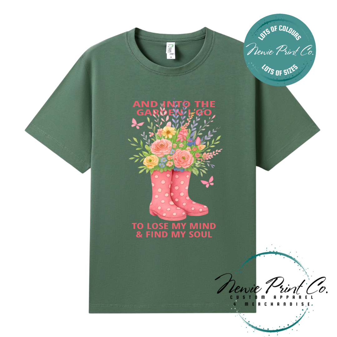 “Into the garden I go to lose my mind and find my soul” quote t-shirt featuring a pair of gumboots filled with wildflowers. Whimsical floral garden design printed on 100% cotton tee using high-quality DTF/DTG print, perfect for nature lovers and gardeners.