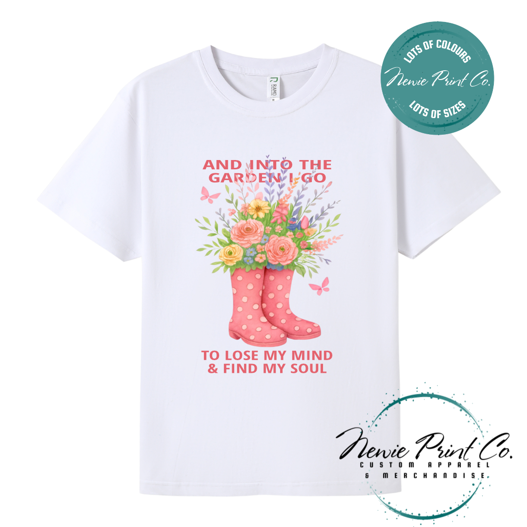 “Into the garden I go to lose my mind and find my soul” quote t-shirt featuring a pair of gumboots filled with wildflowers. Whimsical floral garden design printed on 100% cotton tee using high-quality DTF/DTG print, perfect for nature lovers and gardeners.