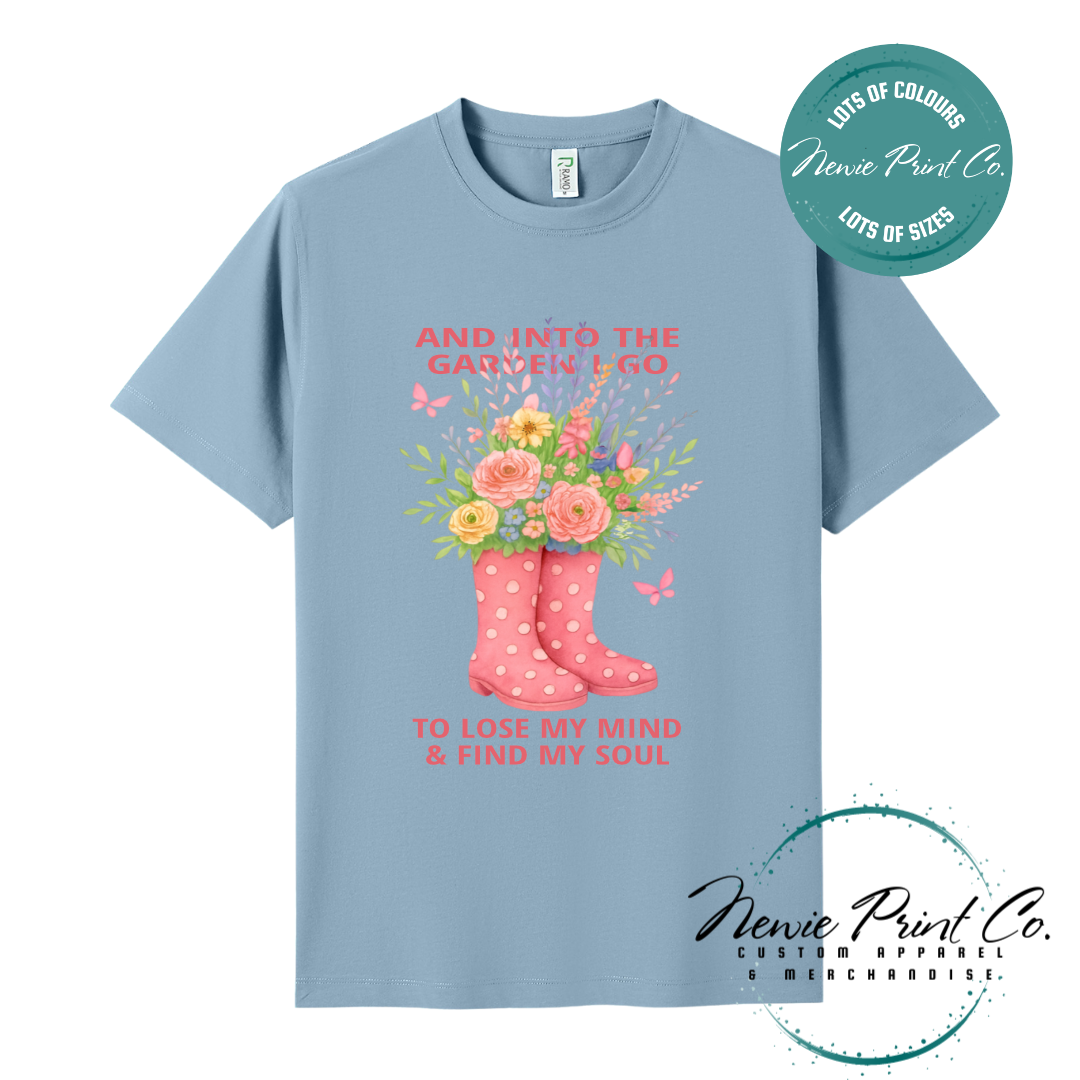 “Into the garden I go to lose my mind and find my soul” quote t-shirt featuring a pair of gumboots filled with wildflowers. Whimsical floral garden design printed on 100% cotton tee using high-quality DTF/DTG print, perfect for nature lovers and gardeners.