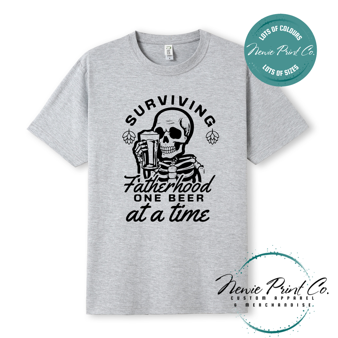 Funny t-shirt and jumper with the phrase “Surviving Fatherhood One Beer at a Time” featuring a skeleton holding a beer. Printed on soft cotton with high-quality DTF/DTG printing. Perfect humorous gift for dads, beer lovers, and Father's Day.