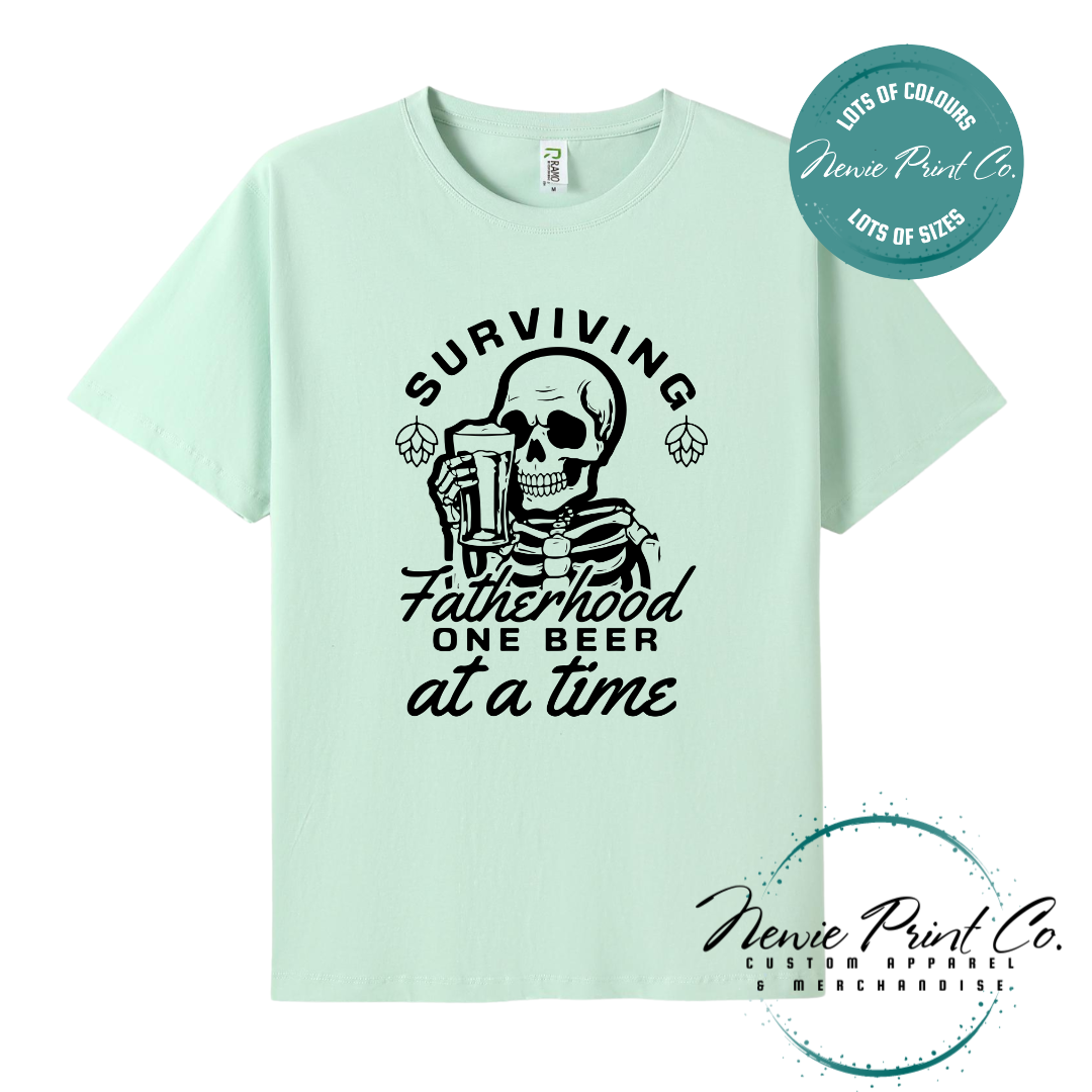 Funny t-shirt and jumper with the phrase “Surviving Fatherhood One Beer at a Time” featuring a skeleton holding a beer. Printed on soft cotton with high-quality DTF/DTG printing. Perfect humorous gift for dads, beer lovers, and Father's Day.