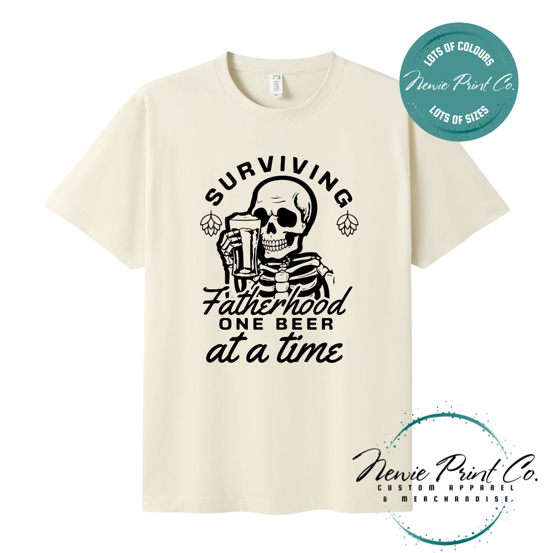 Funny t-shirt and jumper with the phrase “Surviving Fatherhood One Beer at a Time” featuring a skeleton holding a beer. Printed on soft cotton with high-quality DTF/DTG printing. Perfect humorous gift for dads, beer lovers, and Father's Day.