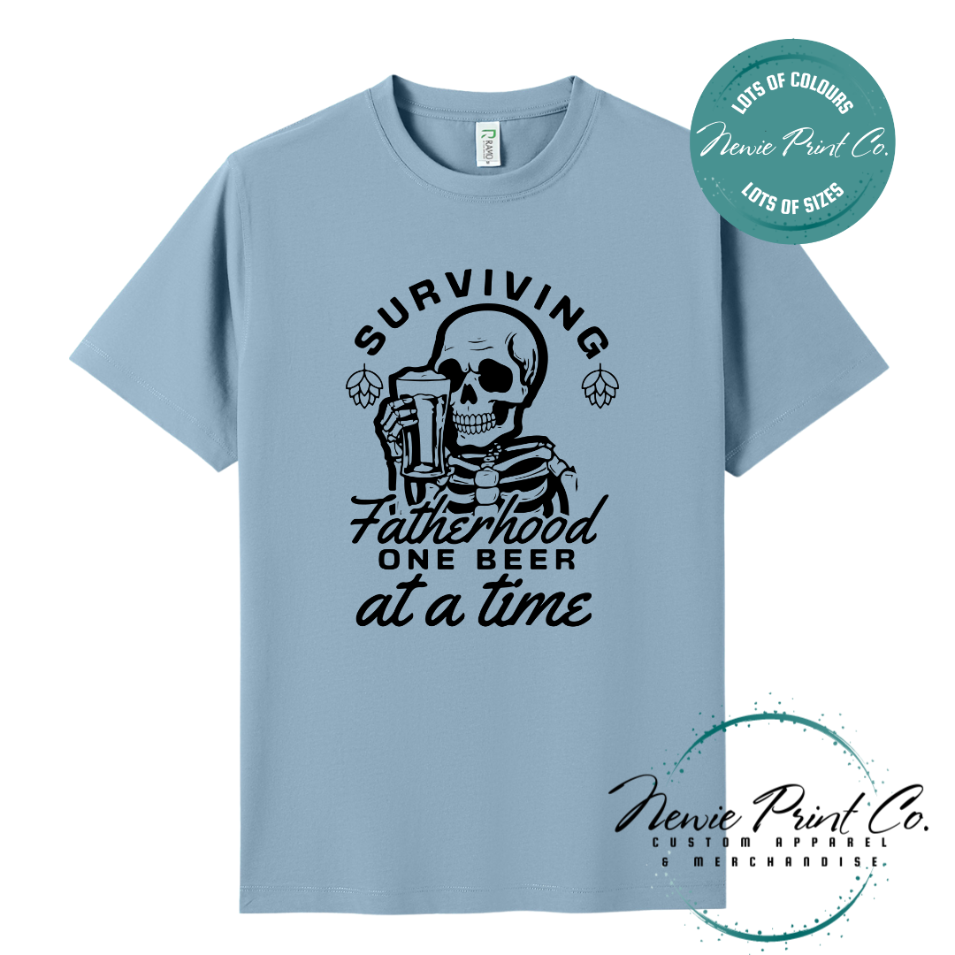 Funny t-shirt and jumper with the phrase “Surviving Fatherhood One Beer at a Time” featuring a skeleton holding a beer. Printed on soft cotton with high-quality DTF/DTG printing. Perfect humorous gift for dads, beer lovers, and Father's Day.