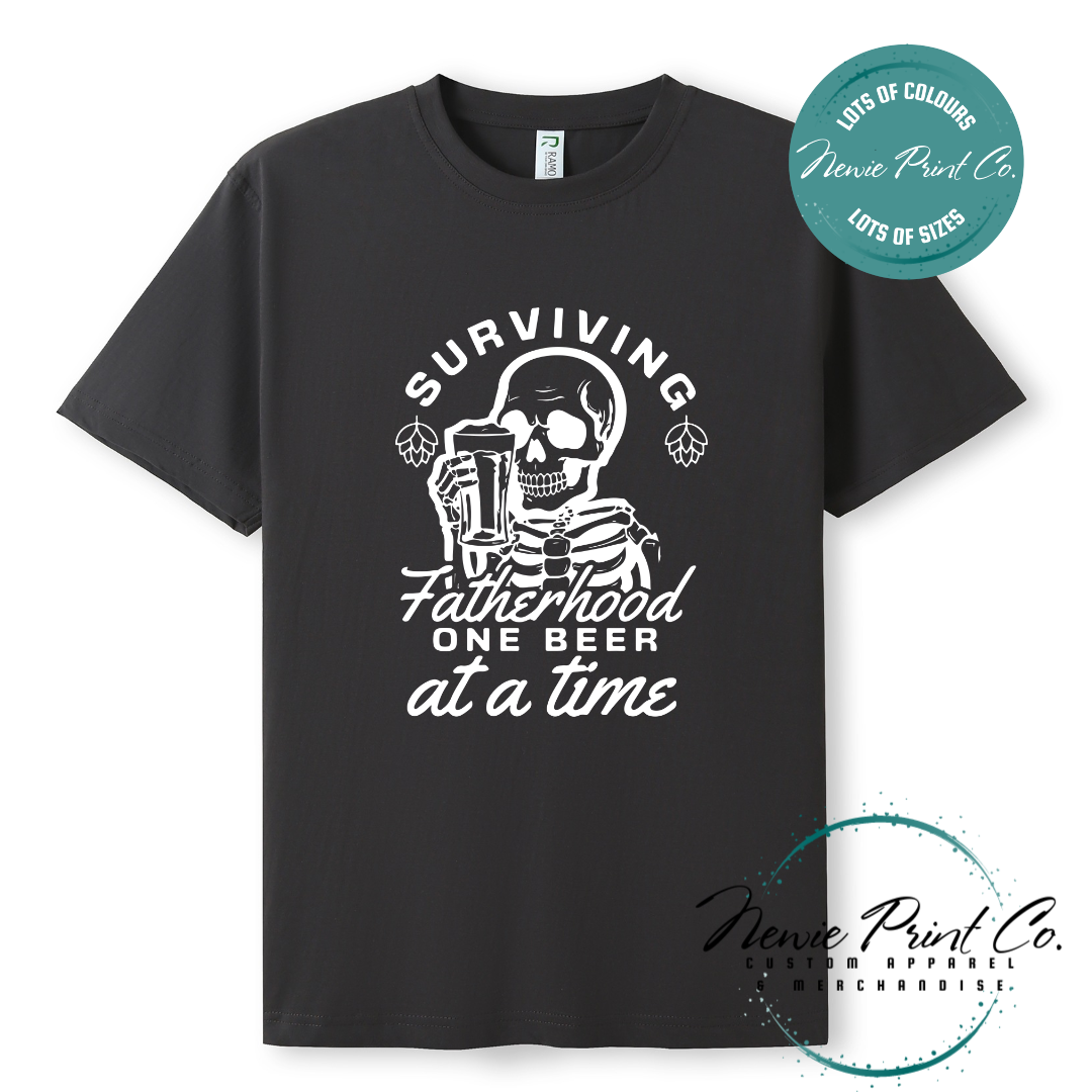 Funny t-shirt and jumper with the phrase “Surviving Fatherhood One Beer at a Time” featuring a skeleton holding a beer. Printed on soft cotton with high-quality DTF/DTG printing. Perfect humorous gift for dads, beer lovers, and Father's Day.