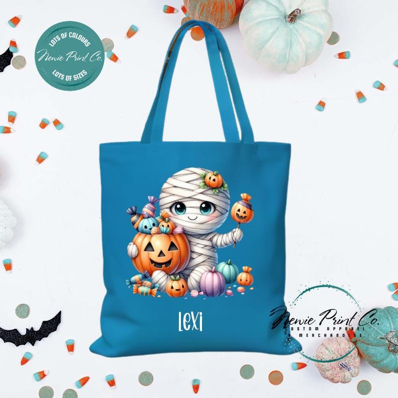 Custom Halloween tote bag with a cute mummy with candy and pumpkins, optional personalised name printed on the front, perfect for trick-or-treating or spooky season gifts printed in Australia.