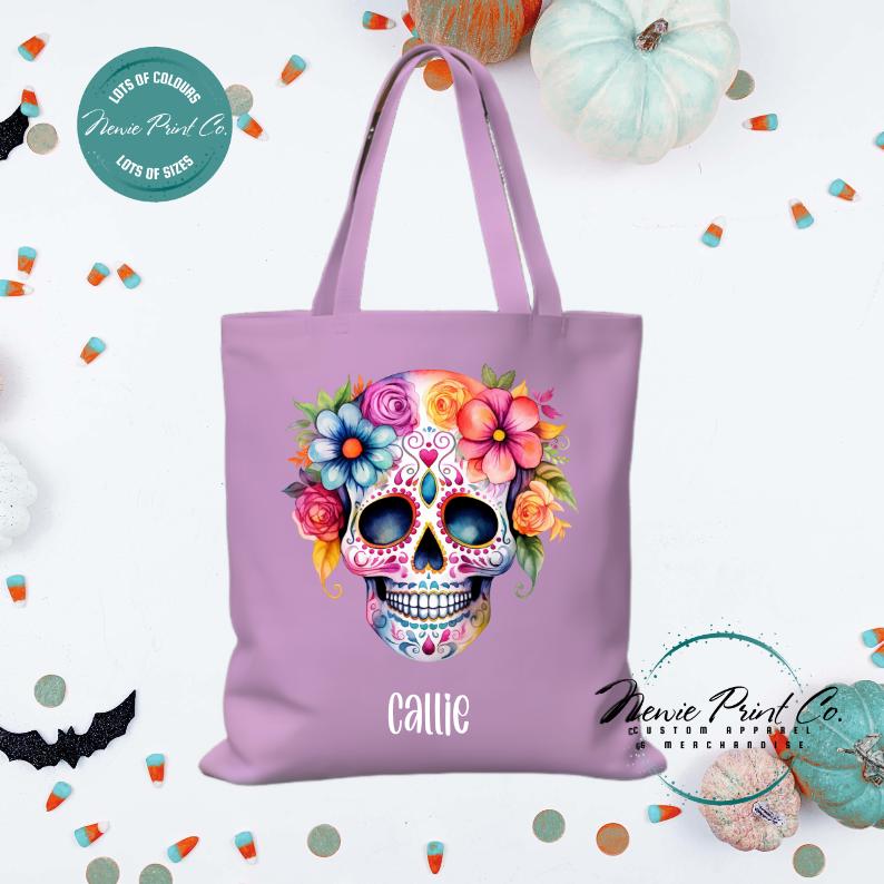 Custom Halloween tote bag with a bright floral sugar skull, optional personalised name printed on the front, perfect for trick-or-treating or spooky season gifts printed in Australia by Newie Print Co.