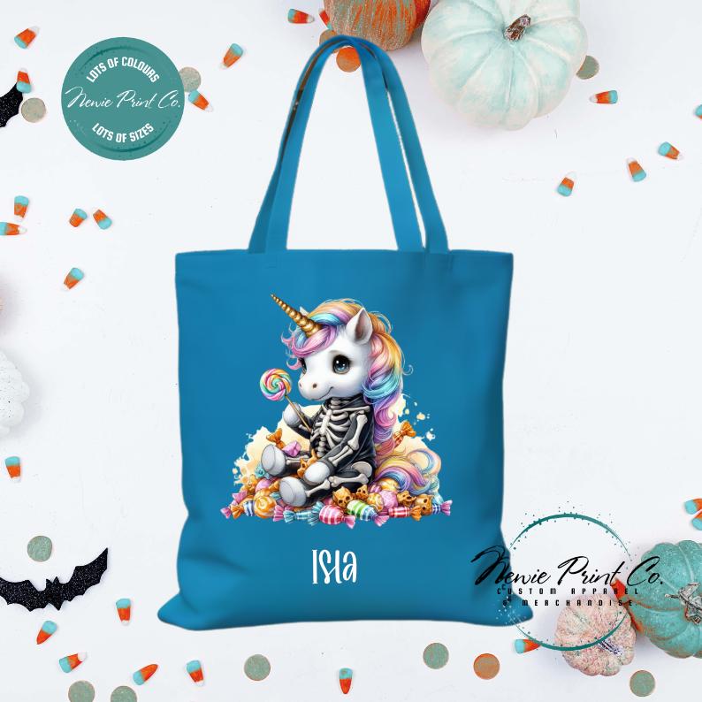 Custom Halloween tote bag with unicorn dressed as a skeleton surrounded by lollies and candy, optional personalised name printed on the front, perfect for trick-or-treating or spooky season gifts