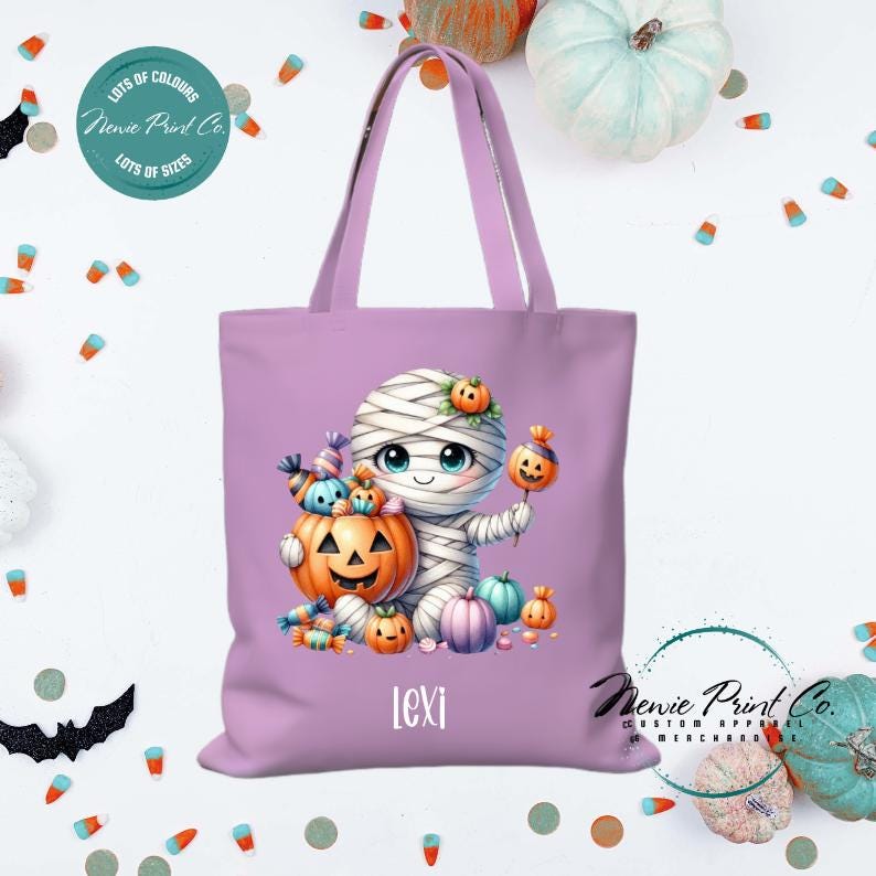 Custom Halloween tote bag with a cute mummy with candy and pumpkins, optional personalised name printed on the front, perfect for trick-or-treating or spooky season gifts printed in Australia by Newie Print Co.