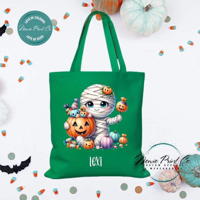 Custom Halloween tote bag with a cute mummy with candy and pumpkins, optional personalised name printed on the front, perfect for trick-or-treating or spooky season gifts printed in Australia by Newie Print Co.
