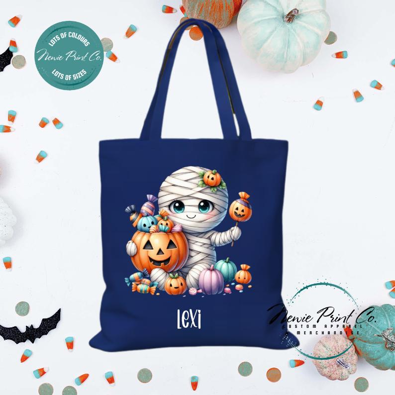Custom Halloween tote bag with a cute mummy with candy and pumpkins, optional personalised name printed on the front, perfect for trick-or-treating or spooky season gifts printed in Australia.