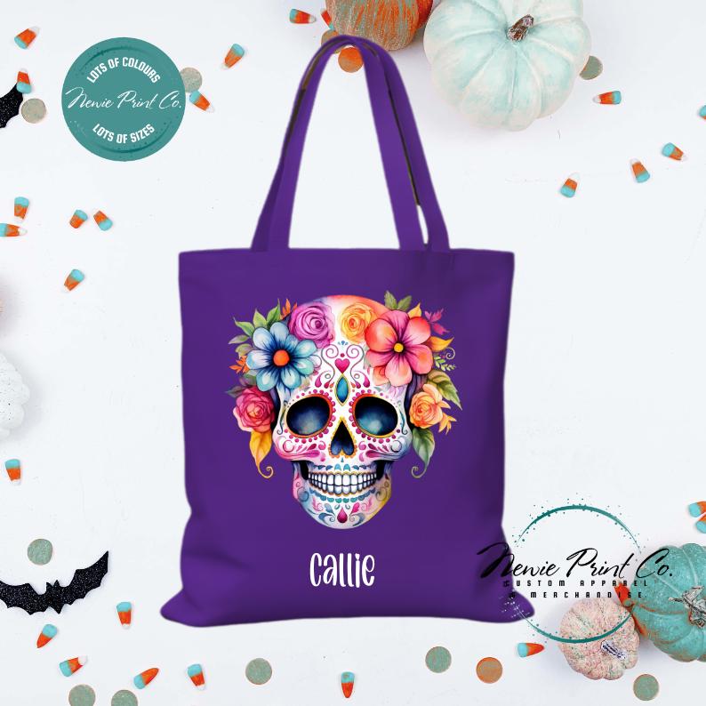 Custom Halloween tote bag with a bright floral sugar skull, optional personalised name printed on the front, perfect for trick-or-treating or spooky season gifts printed in Australia by Newie Print Co.