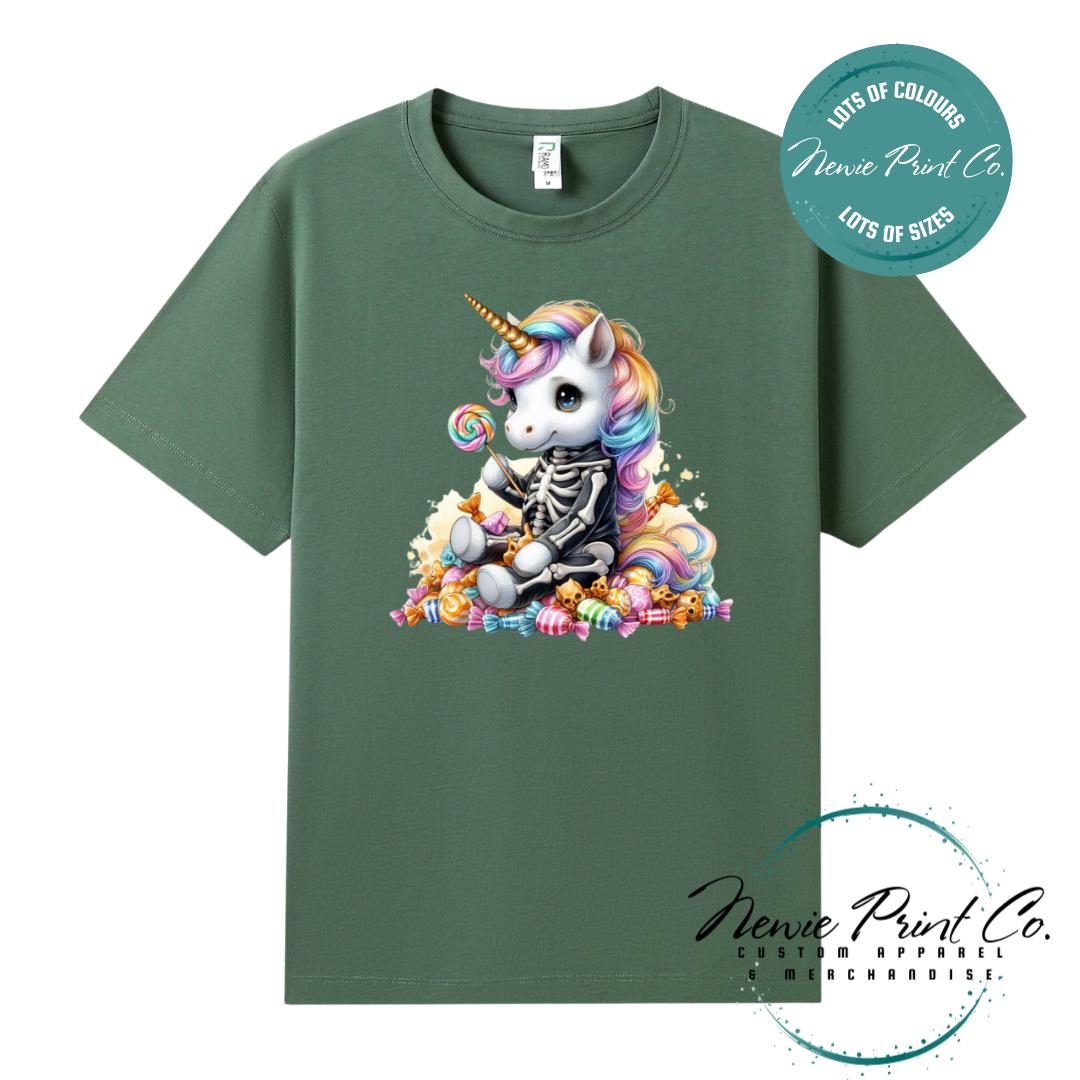 Custom Halloween t-shirts printed in Australia, featuring a cute but spooky unicorn dressed a skeleton sitting on a pile of candy design and optional personalised names — perfect for Halloween parties, school events, or family matching outfits.