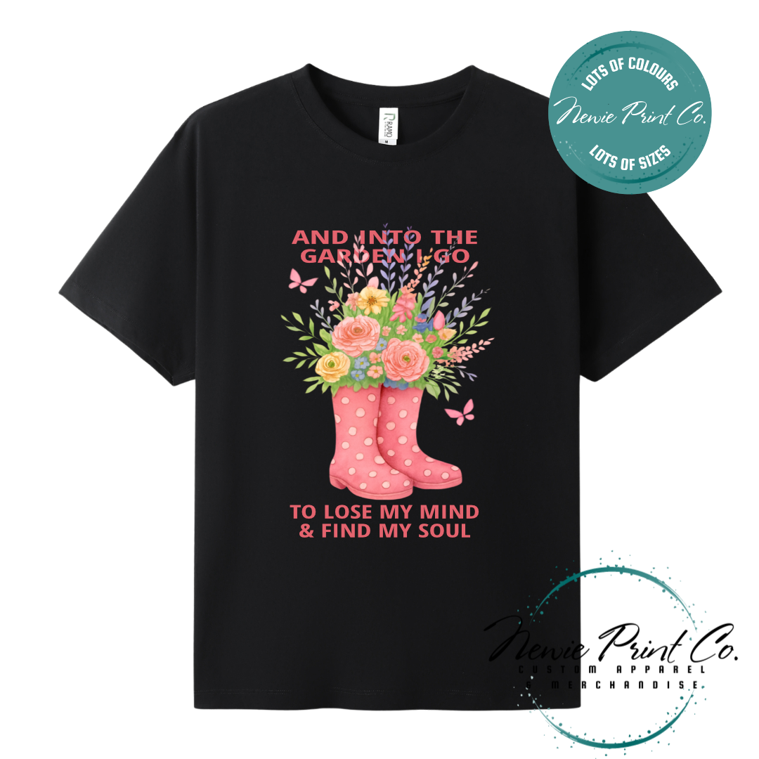 “Into the garden I go to lose my mind and find my soul” quote t-shirt featuring a pair of gumboots filled with wildflowers. Whimsical floral garden design printed on 100% cotton tee using high-quality DTF/DTG print, perfect for nature lovers and gardeners.