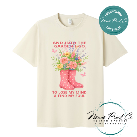 “Into the garden I go to lose my mind and find my soul” quote t-shirt featuring a pair of gumboots filled with wildflowers. Whimsical floral garden design printed on 100% cotton tee using high-quality DTF/DTG print, perfect for nature lovers and gardeners.
