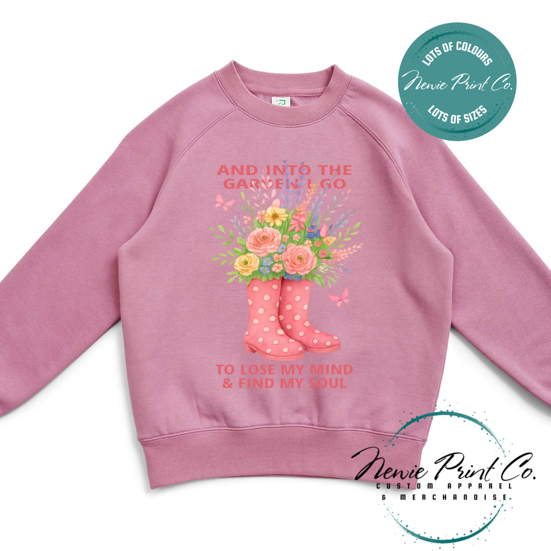 “Into the garden I go to lose my mind and find my soul” quote t-shirt featuring a pair of gumboots filled with wildflowers. Whimsical floral garden design printed on 100% cotton tee using high-quality DTF/DTG print, perfect for nature lovers and gardeners.