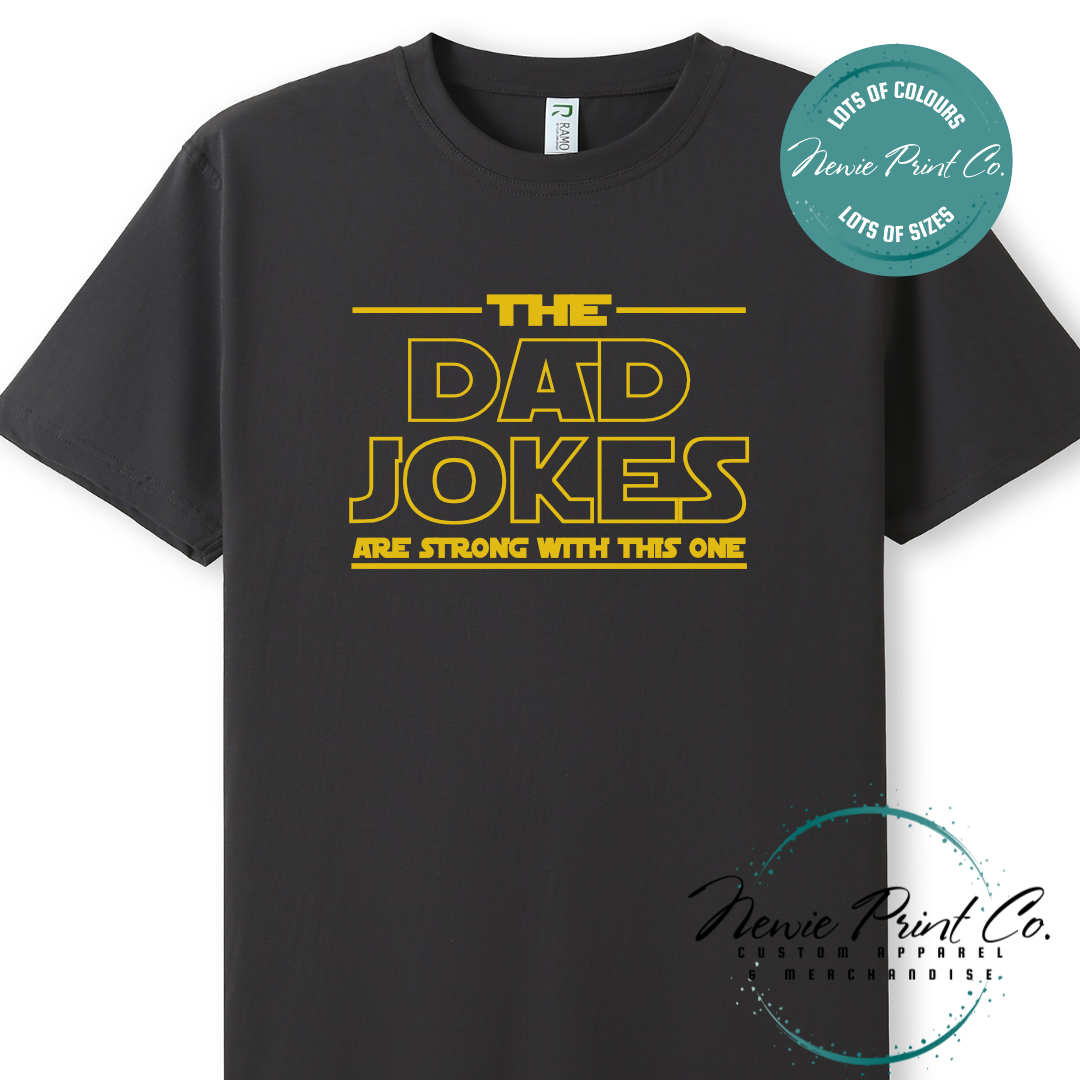 Funny t-shirt and jumper with the text “The Dad Jokes Are Strong With This One”. Humorous Star Wars-inspired quote printed on 100% cotton apparel using high-quality DTF/DTG print. Perfect gift for dads, Father’s Day, or star wars lovers.