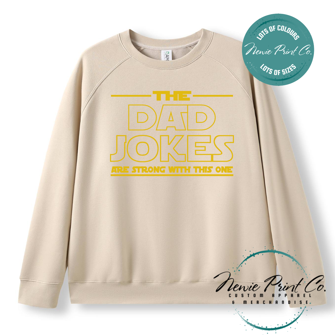 Funny t-shirt and jumper with the text “The Dad Jokes Are Strong With This One”. Humorous Star Wars-inspired quote printed on 100% cotton apparel using high-quality DTF/DTG print. Perfect gift for dads, Father’s Day, or star wars lovers.