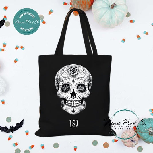 Custom Halloween tote bag with a black and white sugar skull, optional personalised name printed on the front, perfect for trick-or-treating or spooky season gifts printed in Australia by Newie Print Co.