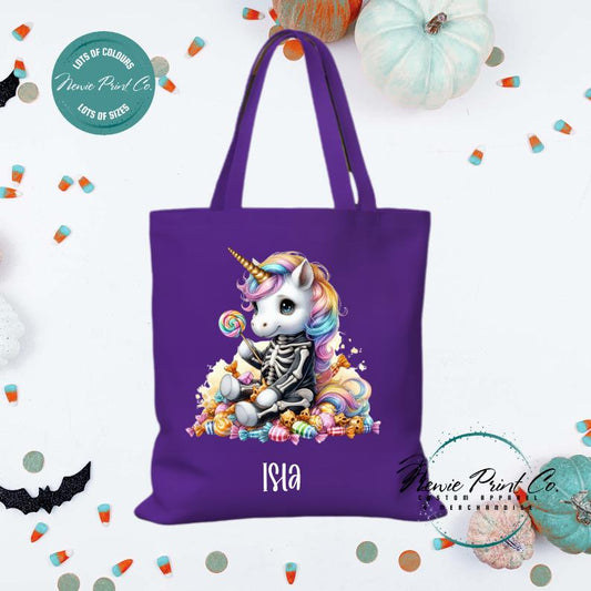 Custom Halloween tote bag with unicorn dressed as a skeleton surrounded by lollies and candy, optional personalised name printed on the front, perfect for trick-or-treating or spooky season gifts