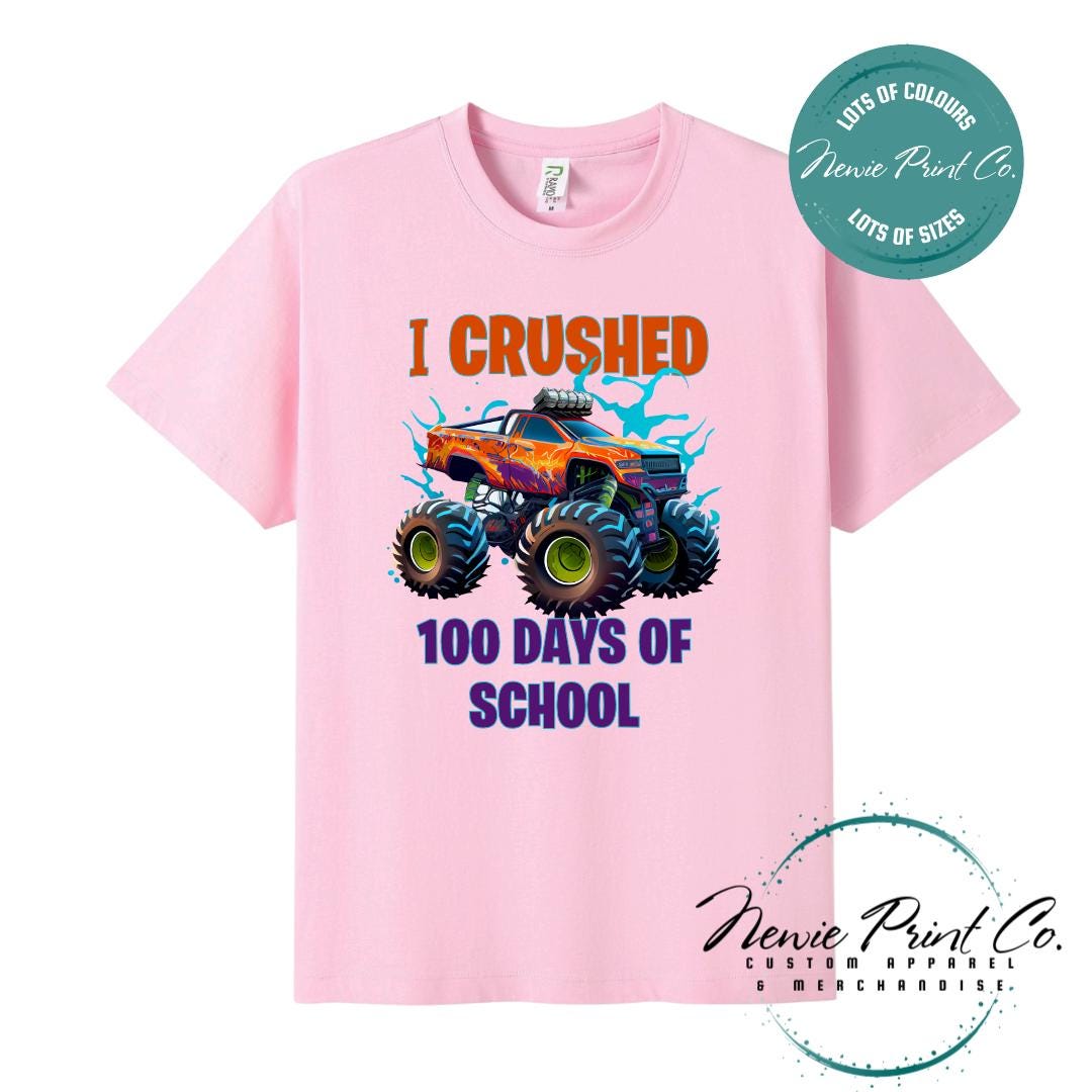 Pink 100 Days of School t-shirt featuring a bold monster truck graphic with the text “I Crushed 100 Days of School,” designed for students or teachers to celebrate the 100th day of school milestone in a fun, playful way. Available in both adult and kids sizes.