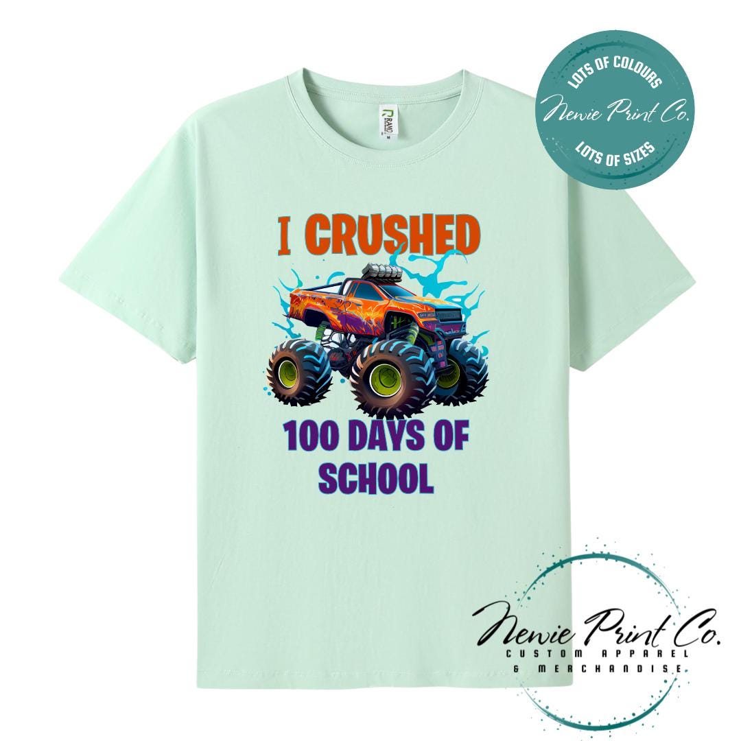 Mint green 100 Days of School t-shirt featuring a bold monster truck graphic with the text “I Crushed 100 Days of School,” designed for students or teachers to celebrate the 100th day of school milestone in a fun, playful way. Available in both adult and kids sizes.