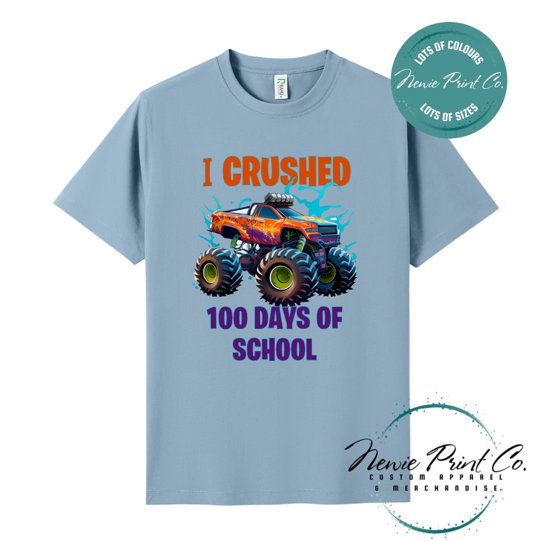 Seafoam Blue 100 Days of School t-shirt featuring a bold monster truck graphic with the text “I Crushed 100 Days of School,” designed for students or teachers to celebrate the 100th day of school milestone in a fun, playful way. Available in both adult and kids sizes.